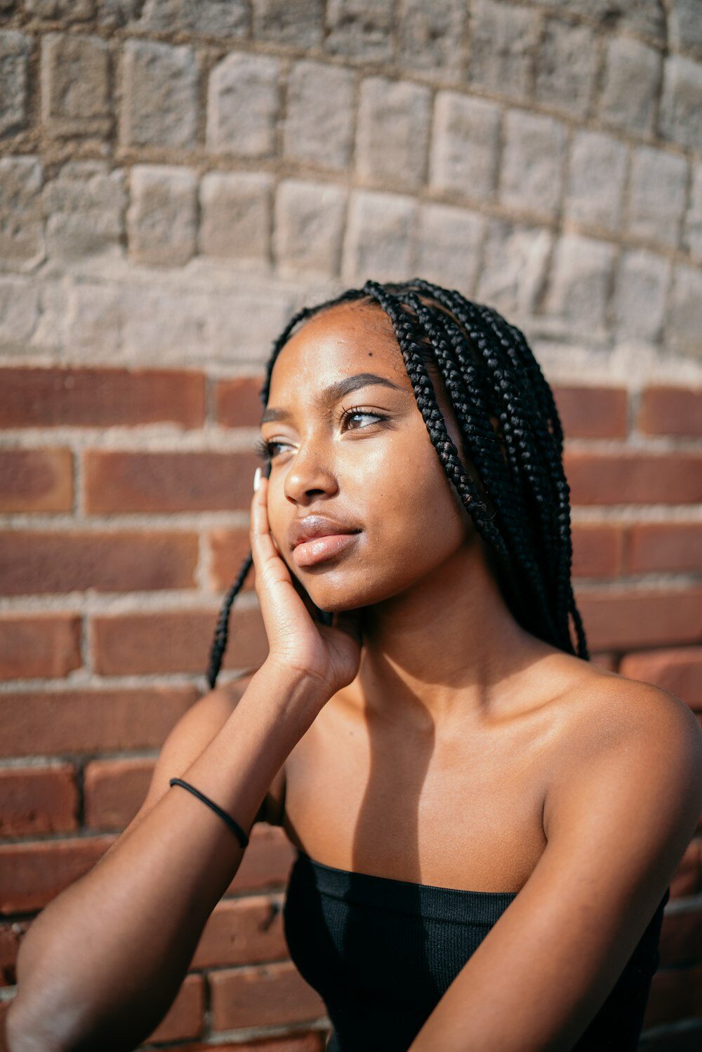 Woman with long braids resting her hand against her face