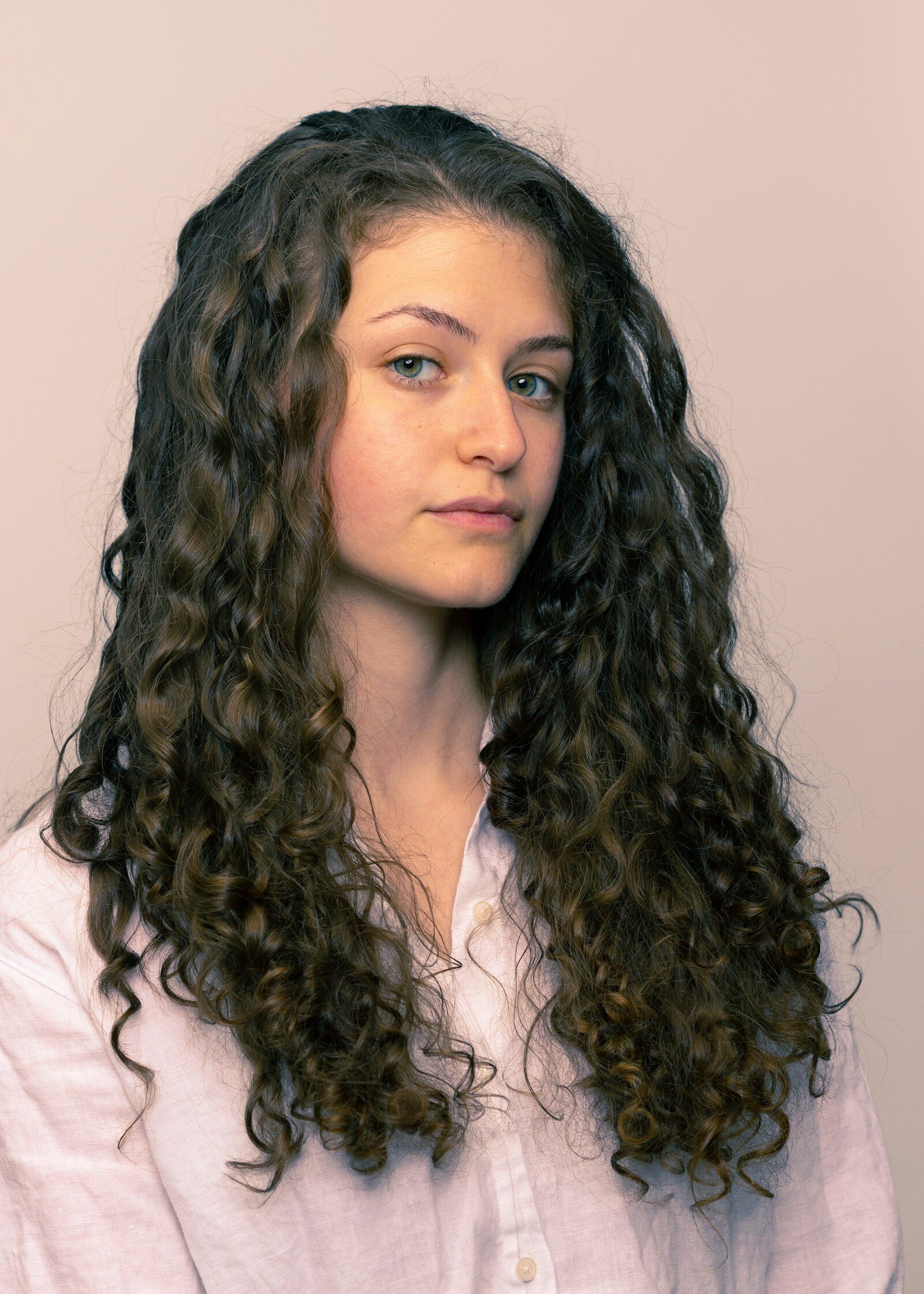 Woman with long, dark, defined curls in soft natural light