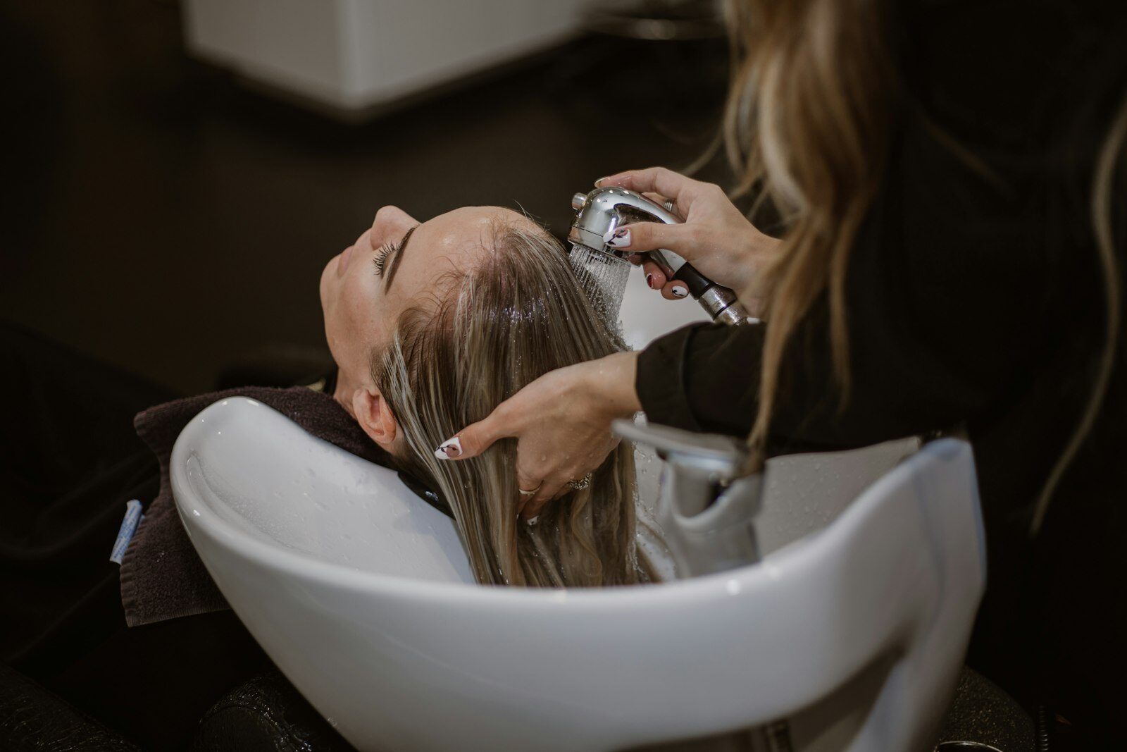Client relaxing at a basin while a stylist washes her hair