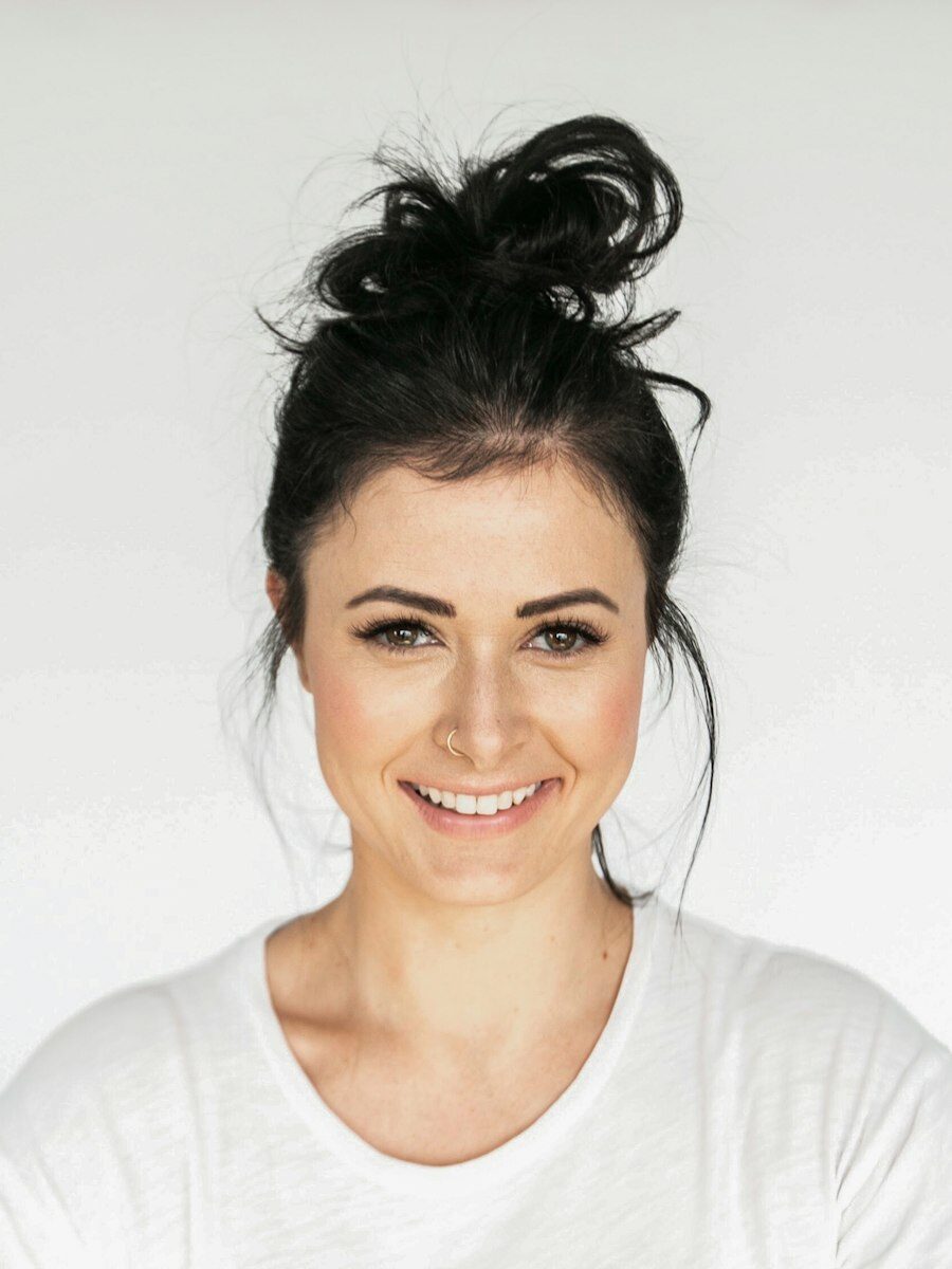 Portrait of Danielle Jacobs smiling, with dark hair tied up in a top knot
