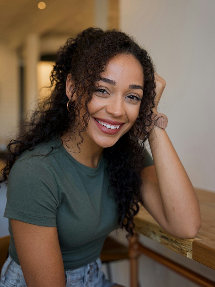 Portrait of Aaliyah Petersen smiling, with long dark curls