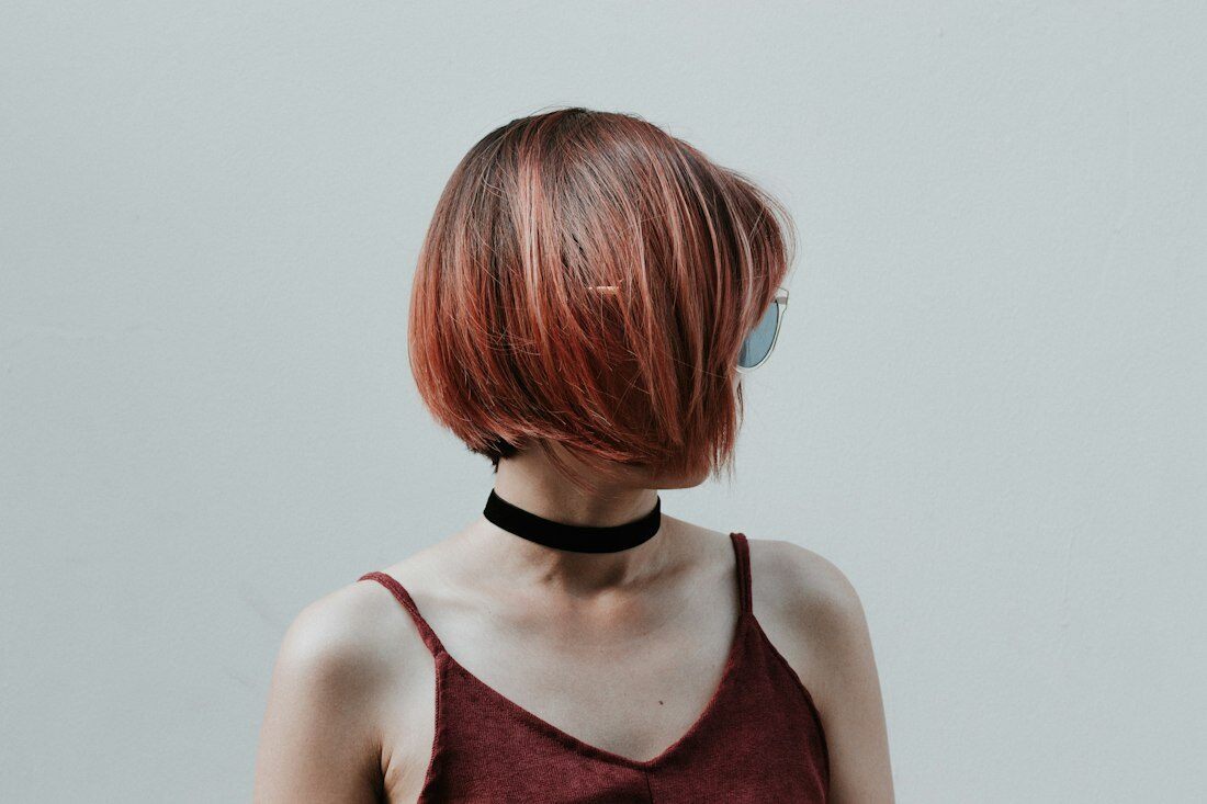 Side view of a woman with a sharp copper bob
