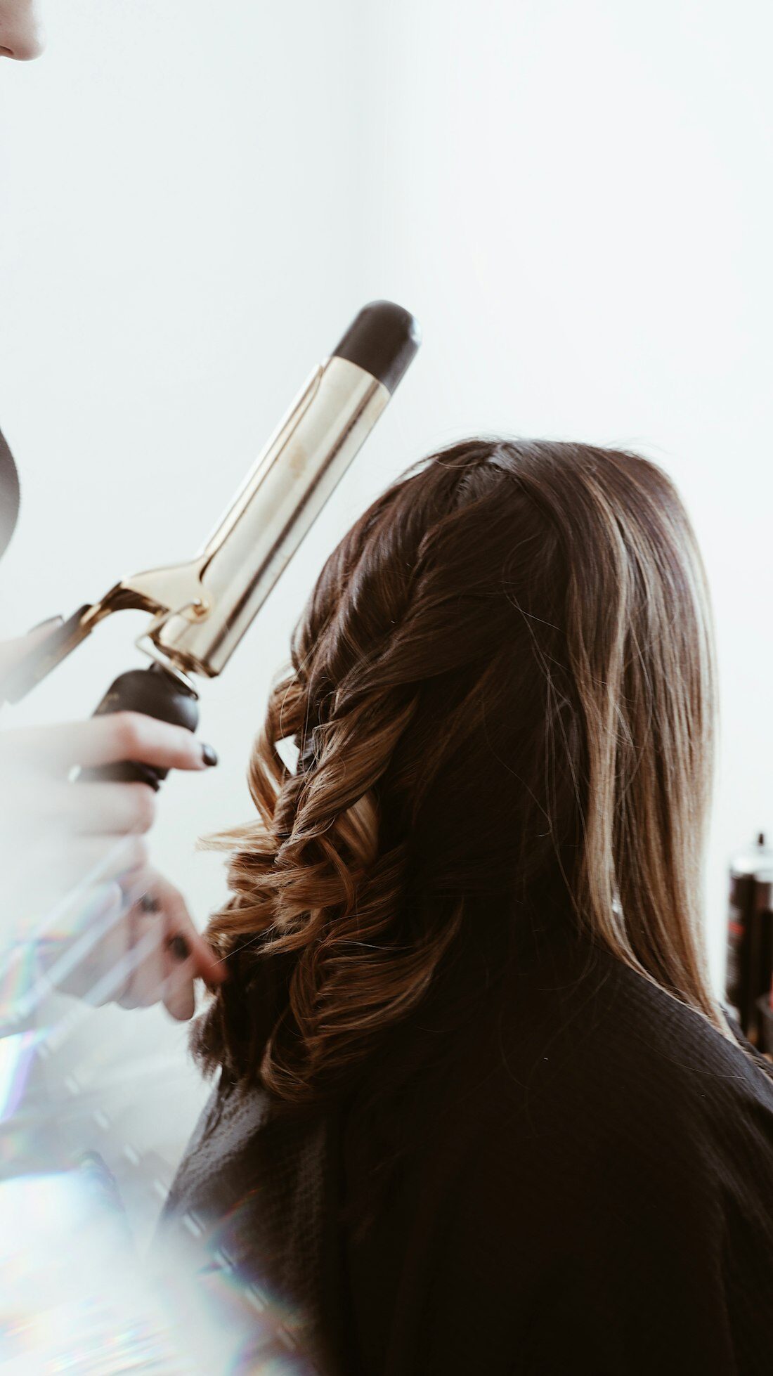 Stylist curling long brunette hair with a curling iron
